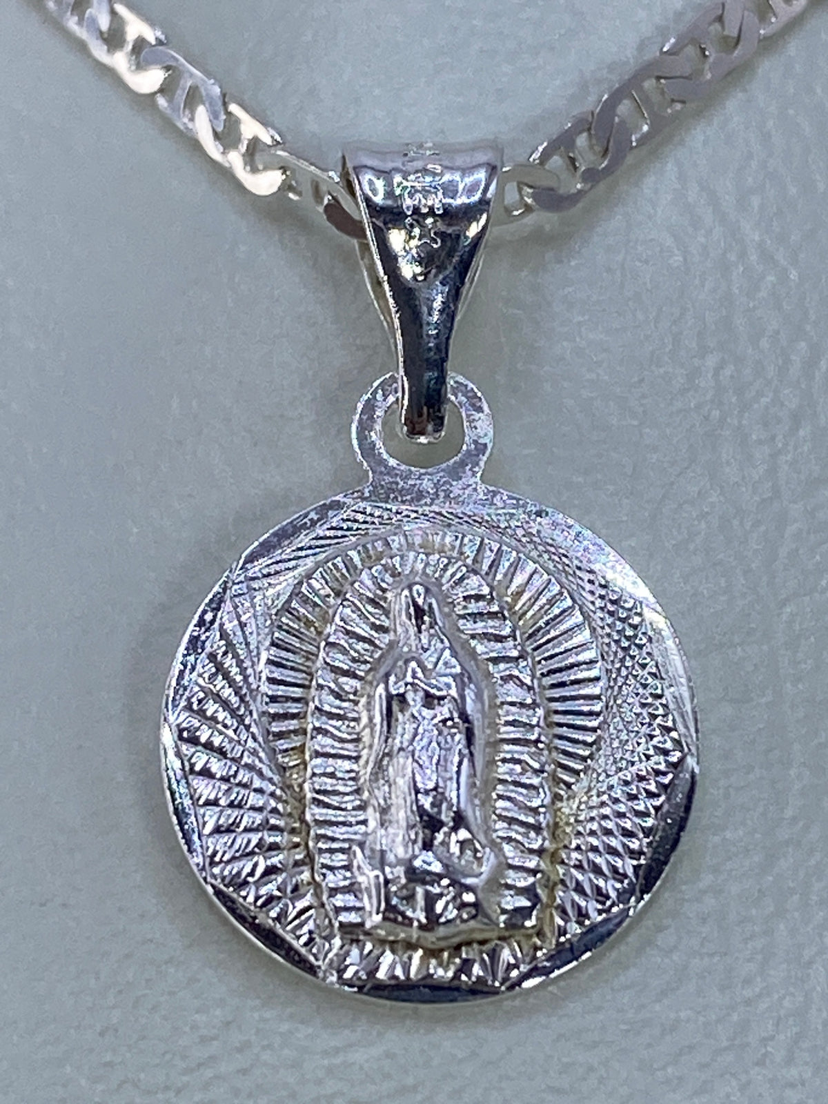 Vista lateral del dije de repujado con la figura de la Virgen