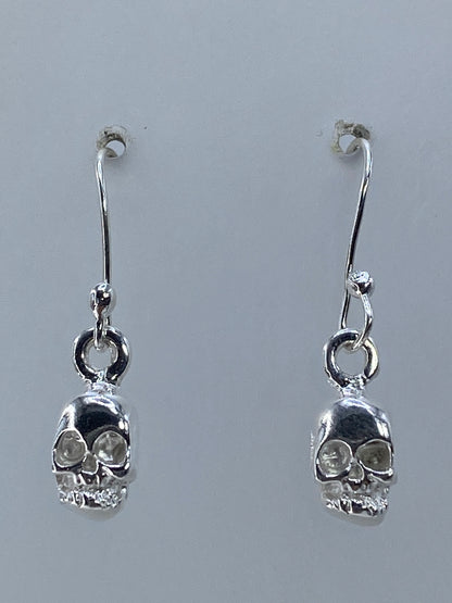 Par de aretes de plata con calavera repujada, largo 2.5 cm, en gancho plateado