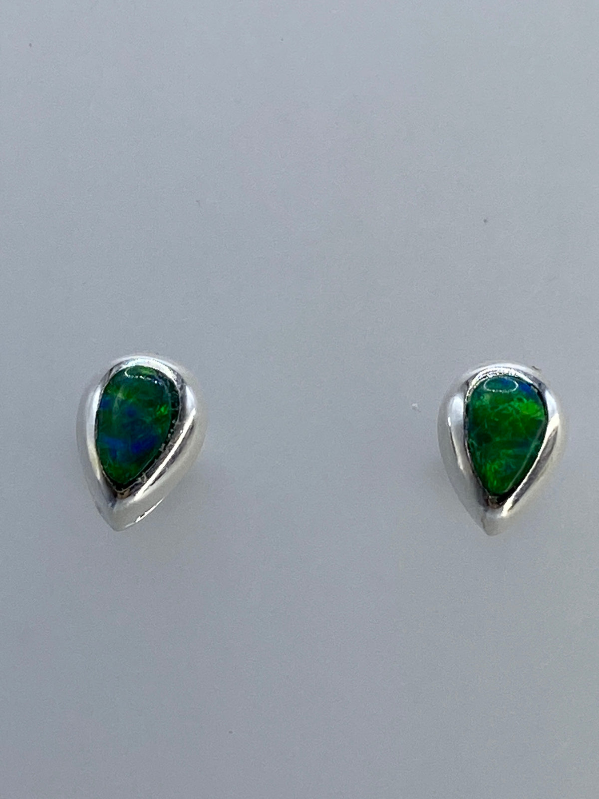 Par de aretes de plata con ópalo de fuego multicolor verde y azul sobre fondo gris