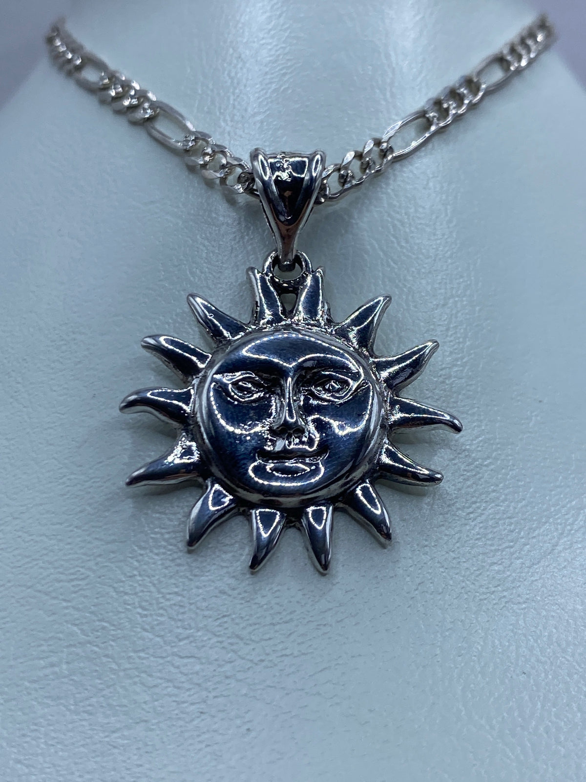 Detalle del dije de sol mostrando el labrado artesanal de los ojos y la boca