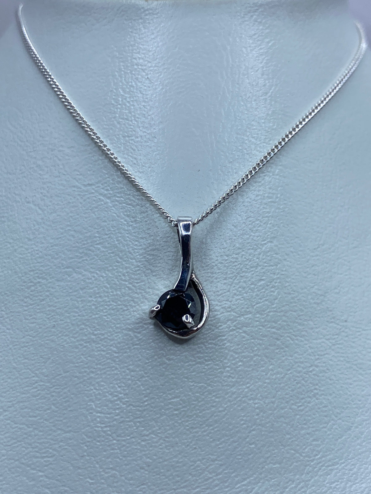 Vista frontal del dije minimalista en plata, circonia negra brillante