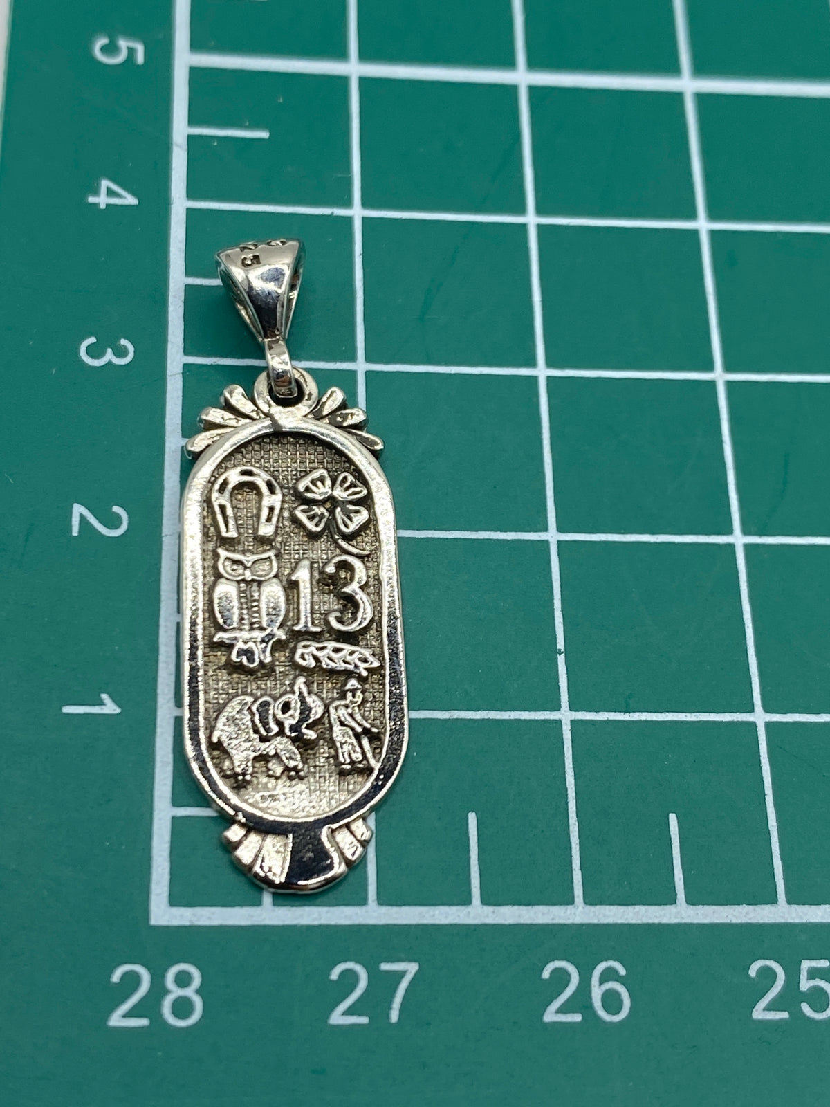 Dije de plata prehispánico aislado sobre fondo blanco con herraje de colgador