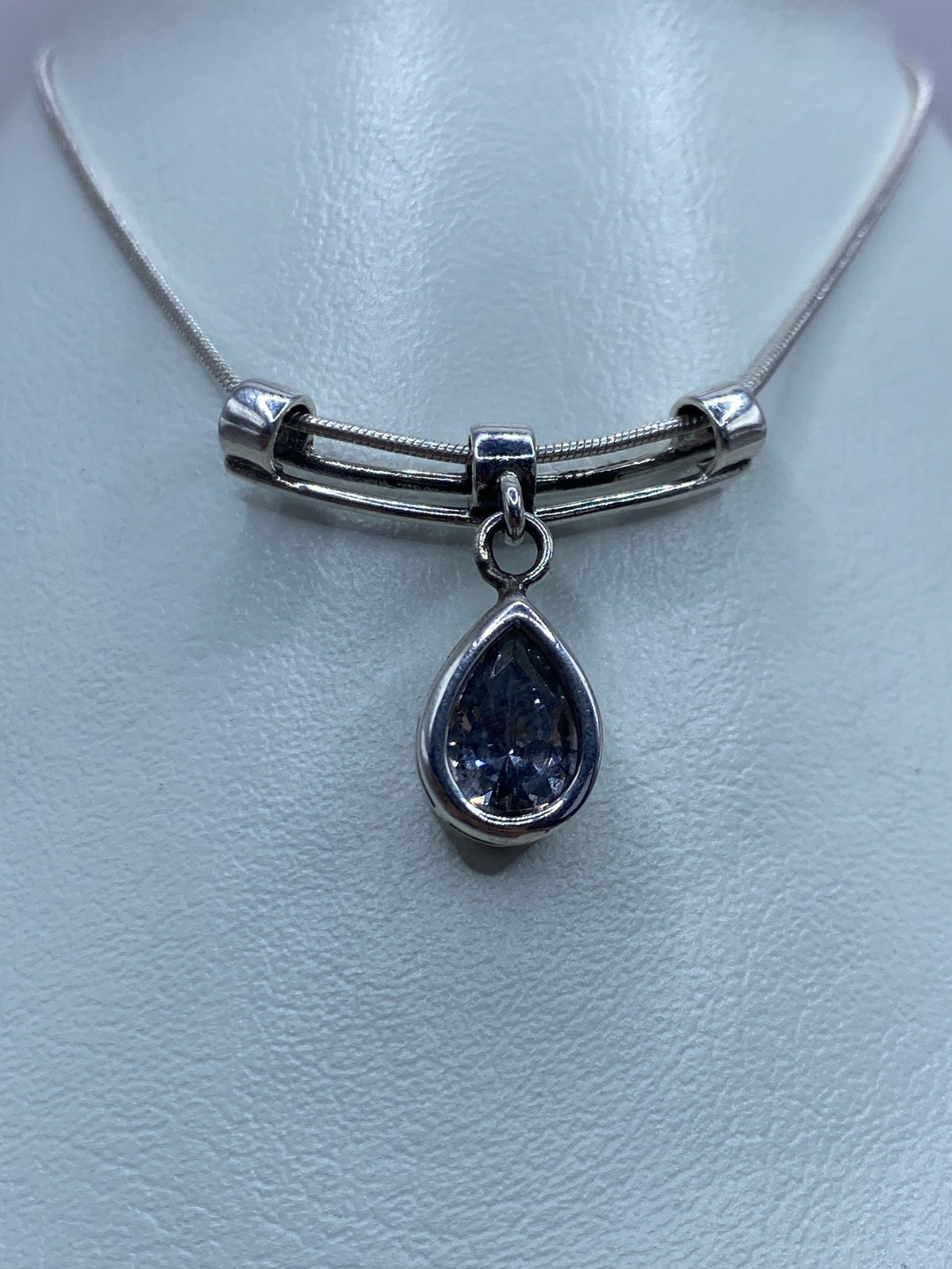 Detalle frontal del dije con circonia facetada reflejando luz, engastado en plata 925