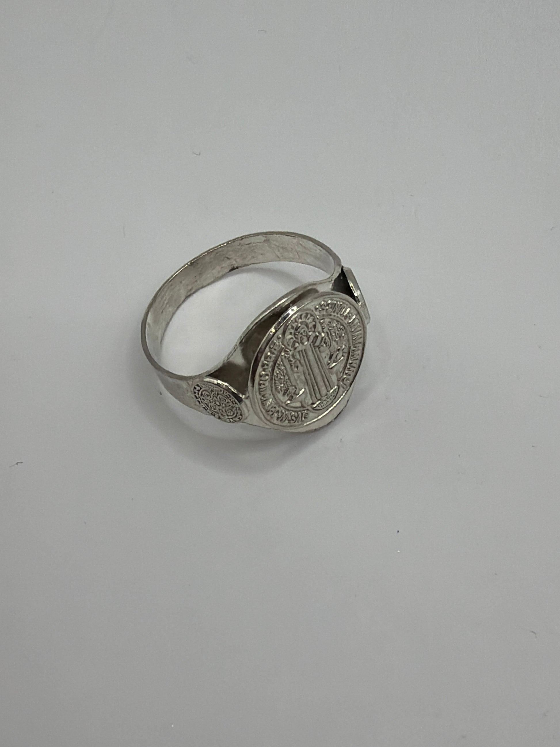 Anillo San Benito de perfil mostrando el aro liso y el simbolo en relieve, acabado pulido