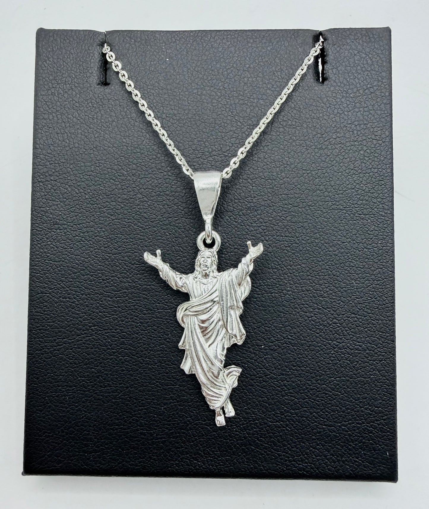 Collar Cristo de plata .925 sobre caja gris oscuro, cadena de eslabones rectangulares, Cristo con brazos elevados