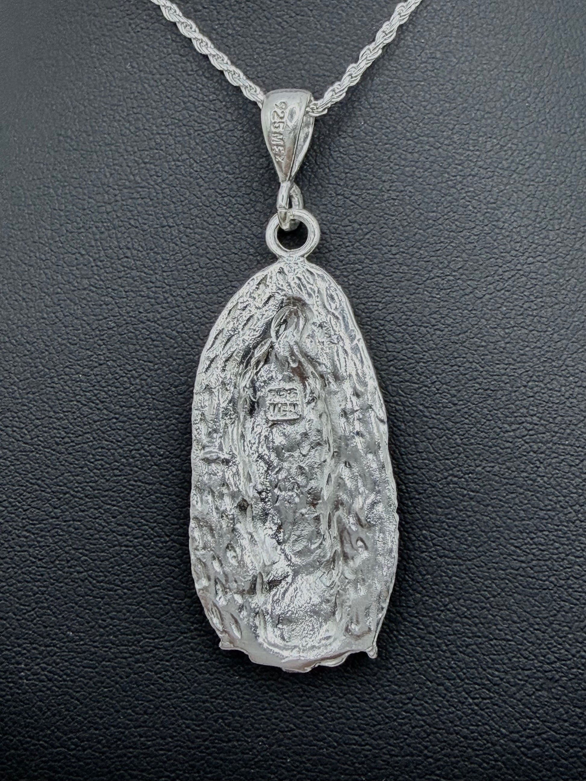 Detalle frontal del dije Virgen Guadalupe repujado con profundidad artesanal, relieve tallado en plata pura