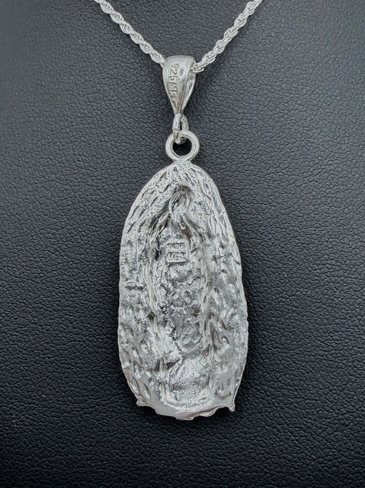 Detalle frontal del dije Virgen Guadalupe repujado con profundidad artesanal, relieve tallado en plata pura