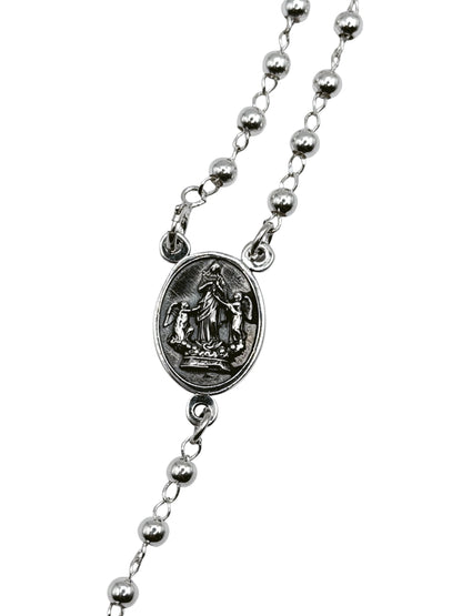 Detalle del medallón ovalado con grabado de Virgen Desatanudos y crucifijo de plata