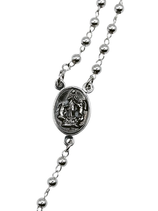 Detalle del medallón ovalado con grabado de Virgen Desatanudos y crucifijo de plata