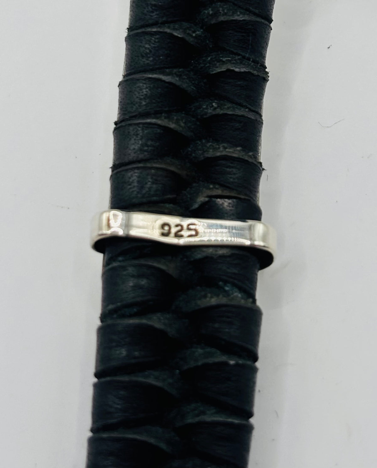 Detalle cercano de la banda de plata .925 grabada con patrón étnico, sobre piel oscura