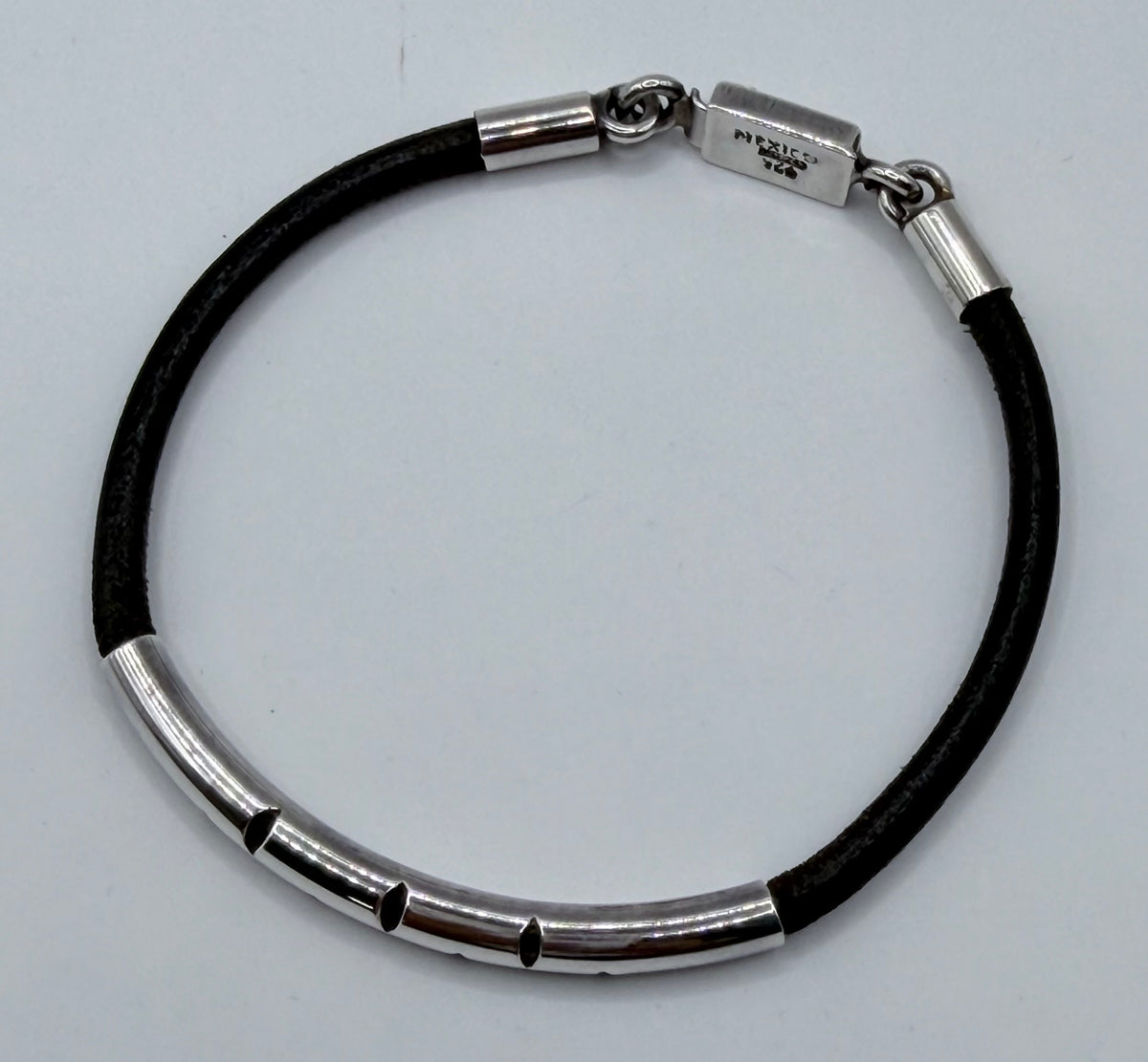 Vista lateral y abierta de la pulsera mostrando eslabones plateados alternados con segmentos de caucho negro