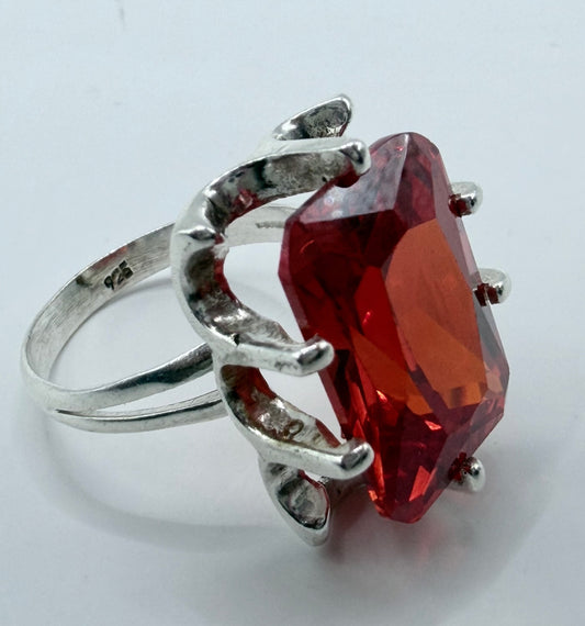 Detalle lateral del anillo circonia roja mostrando el volumen del diseño tipo caramelo y el hallmark .925